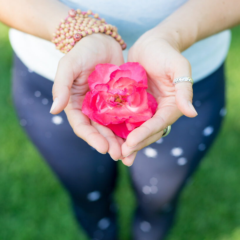 fille en tenue de yoga, dans la anture, avec fleur a la main, rose et vert